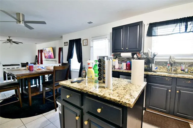 a kitchen with stainless steel appliances kitchen island granite countertop a refrigerator a stove and a dining table with wooden floor