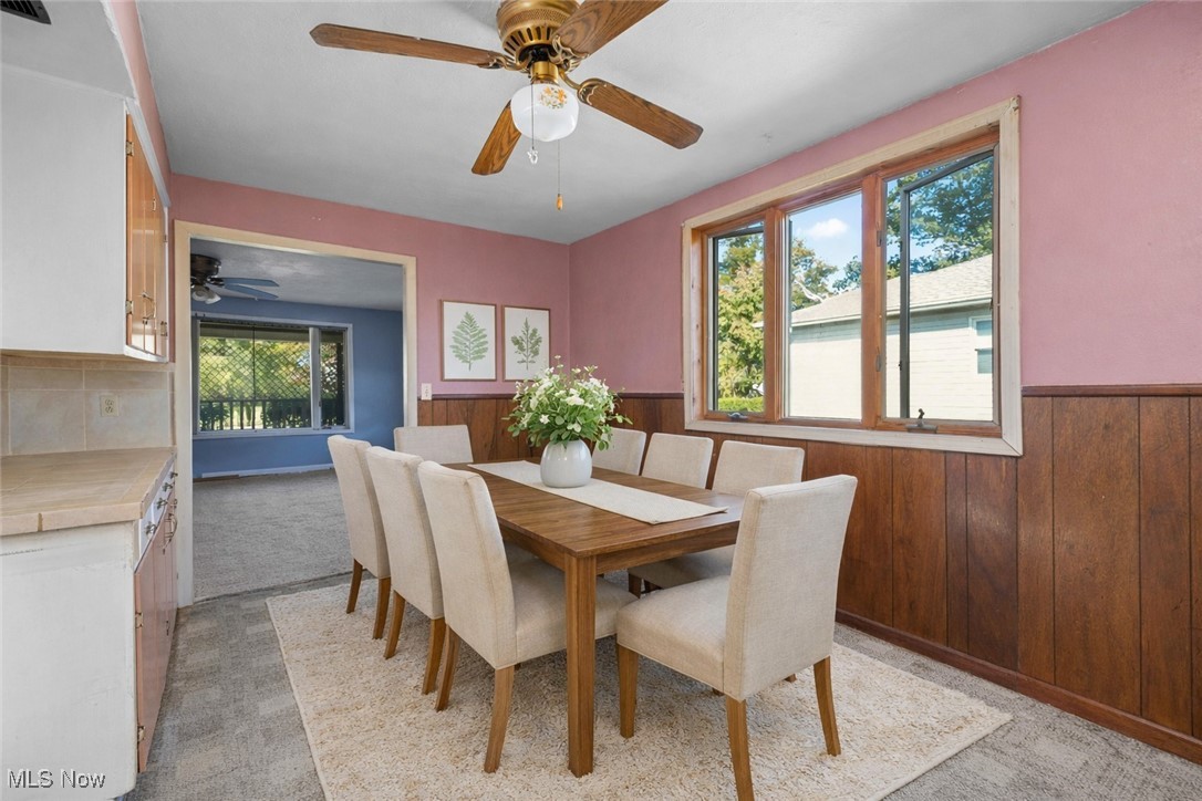 6927 North Wildacre Road Curtice, OH 43412 - Photo 6 of 44 Dining space with wood walls, light carpet, a wainscoted wall, and a ceiling fan