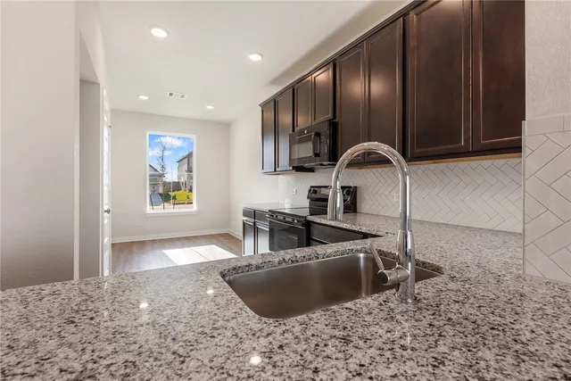 a kitchen with granite countertop a sink stainless steel appliances and cabinets