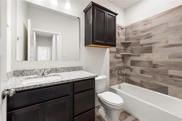a bathroom with a granite countertop toilet sink and mirror