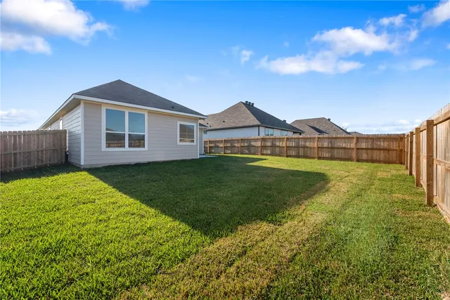 a view of a yard in front of a house with a large tree