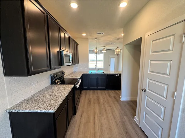 a large kitchen with a center island wooden floor and stainless steel appliances