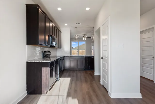 a kitchen with stainless steel appliances granite countertop a stove a sink and a refrigerator