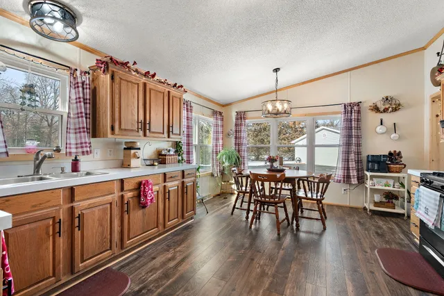 a kitchen with stainless steel appliances granite countertop a stove top oven a sink dishwasher a dining table and chairs with wooden floor