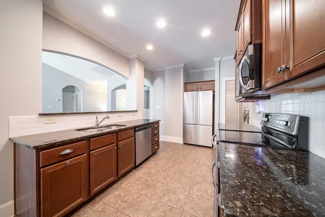 a large kitchen with stainless steel appliances a large counter top a stove and a refrigerator