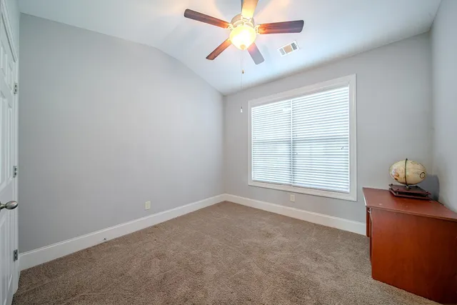 an empty room with windows and fan