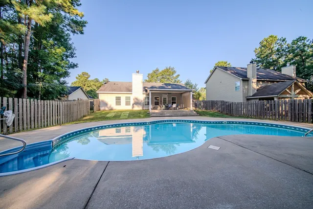 a view of a house with pool and a yard