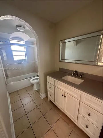 a bathroom with a granite countertop toilet sink and mirror