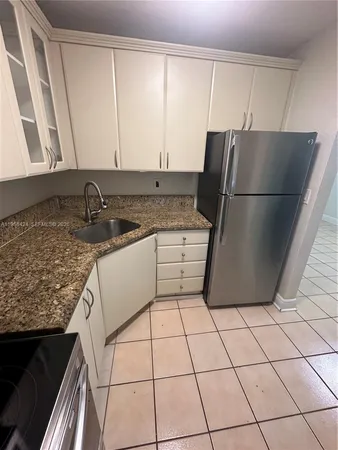 a kitchen with a sink a refrigerator and cabinets