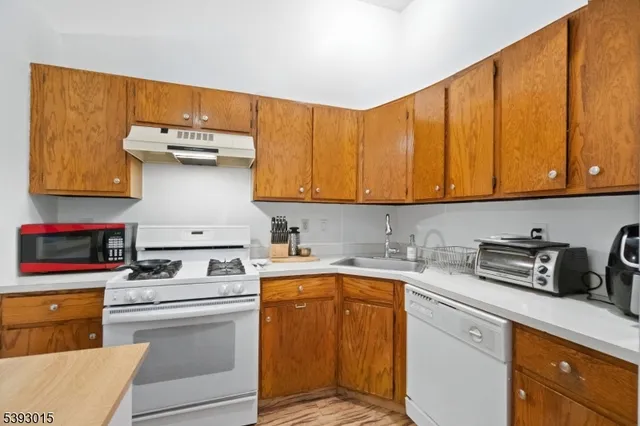 a kitchen with stainless steel appliances a stove a sink and white cabinets