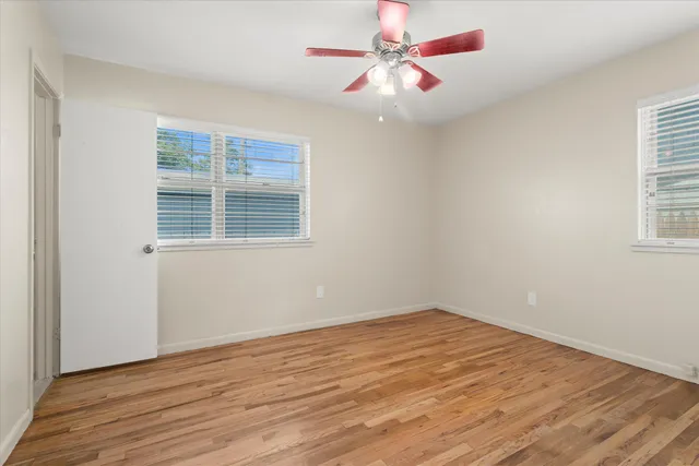 a view of an empty room with wooden floor and a window