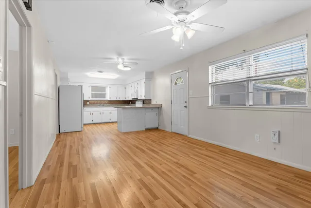 a view of kitchen and empty room with wooden floor