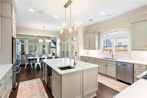 a kitchen with a stove a sink a refrigerator and a dining table with wooden floor