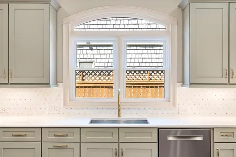 a kitchen with stainless steel appliances a stove a sink dishwasher a refrigerator and white cabinets with wooden floor