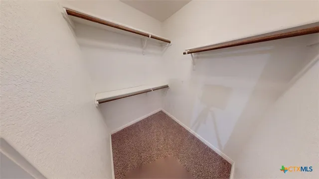 a view of a large pool with lawn chairs under an umbrella