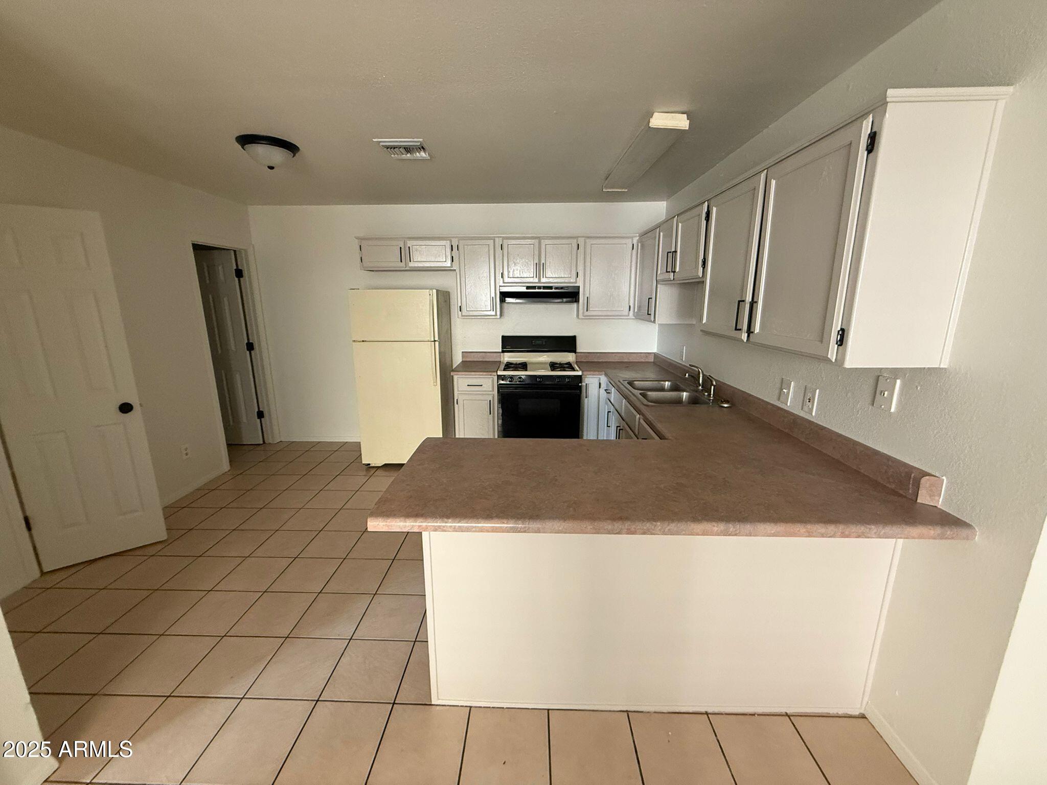 712 East 17th Street, Unit D Douglas, AZ 85607 - Photo 4 of 16 a kitchen with stainless steel appliances granite countertop a refrigerator a stove a sink a microwave and white cabinets