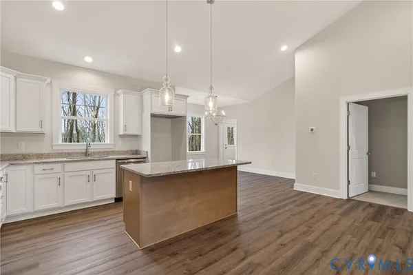 a large kitchen with stainless steel appliances granite countertop a stove a sink dishwasher and a refrigerator with wooden floor