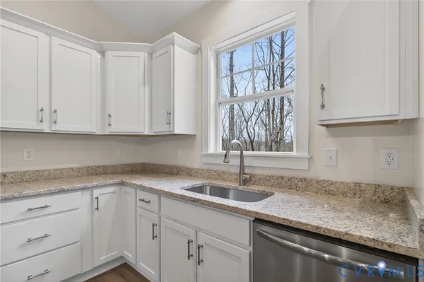 a kitchen with granite countertop white cabinets and a stove