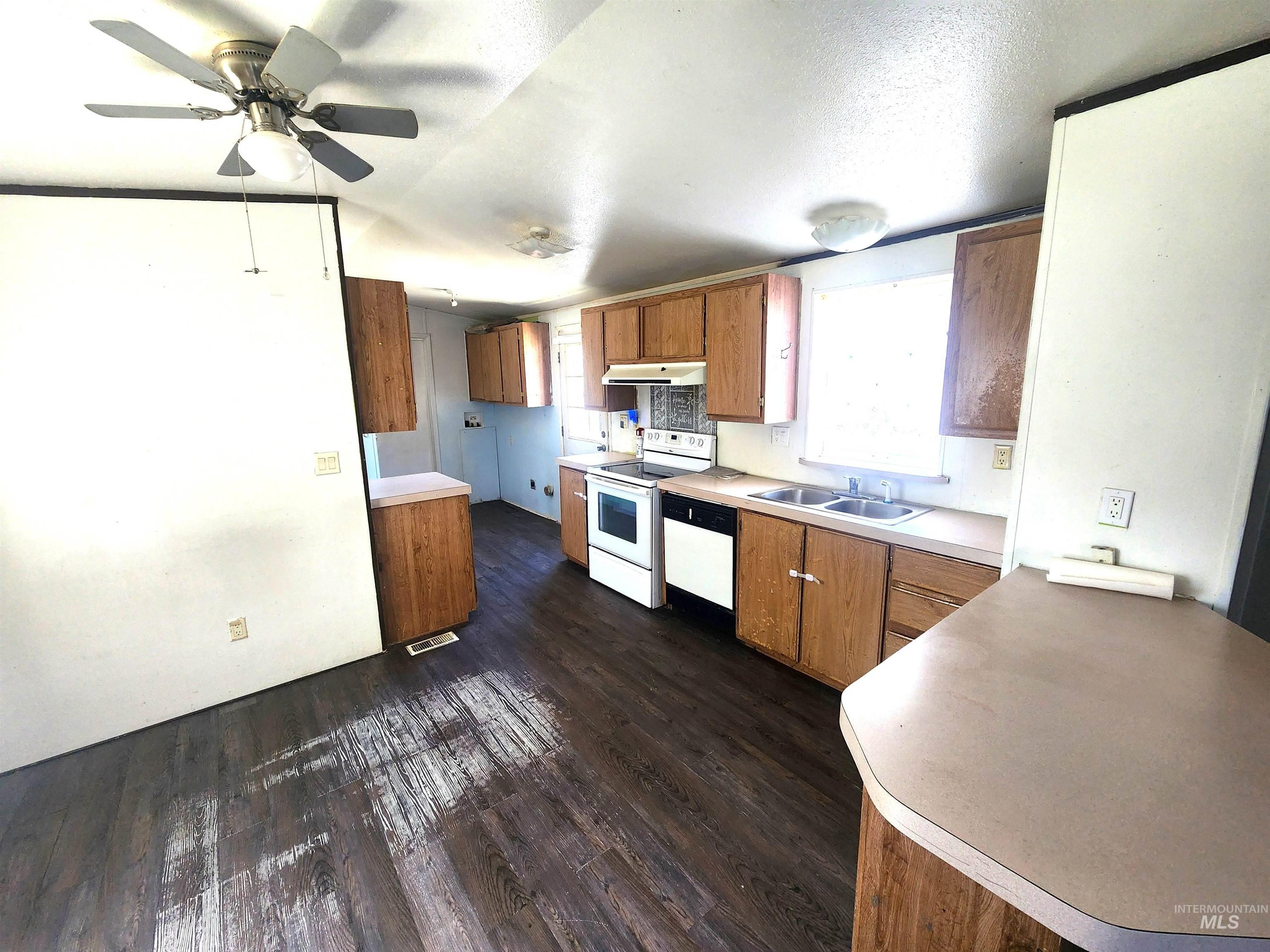 616 North Kings Road Nampa, ID 83687 - Photo 3 of 12 Kitchen featuring wood-finish flooring, wood cabinetry, laminate countertops, a double basin sink, and a white oven/stove