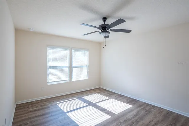 a view of empty room with wooden floor and fan