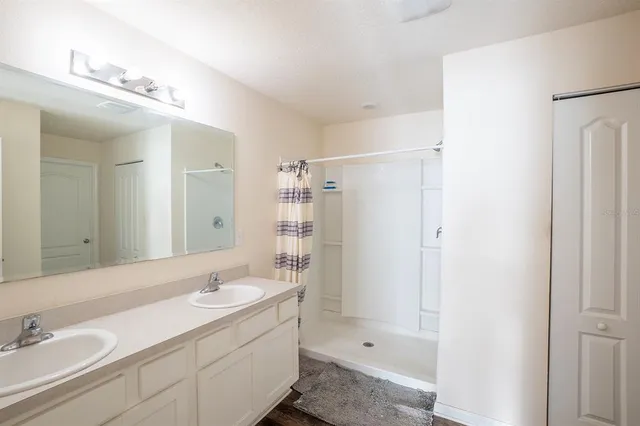 a bathroom with a double vanity sink mirror and shower