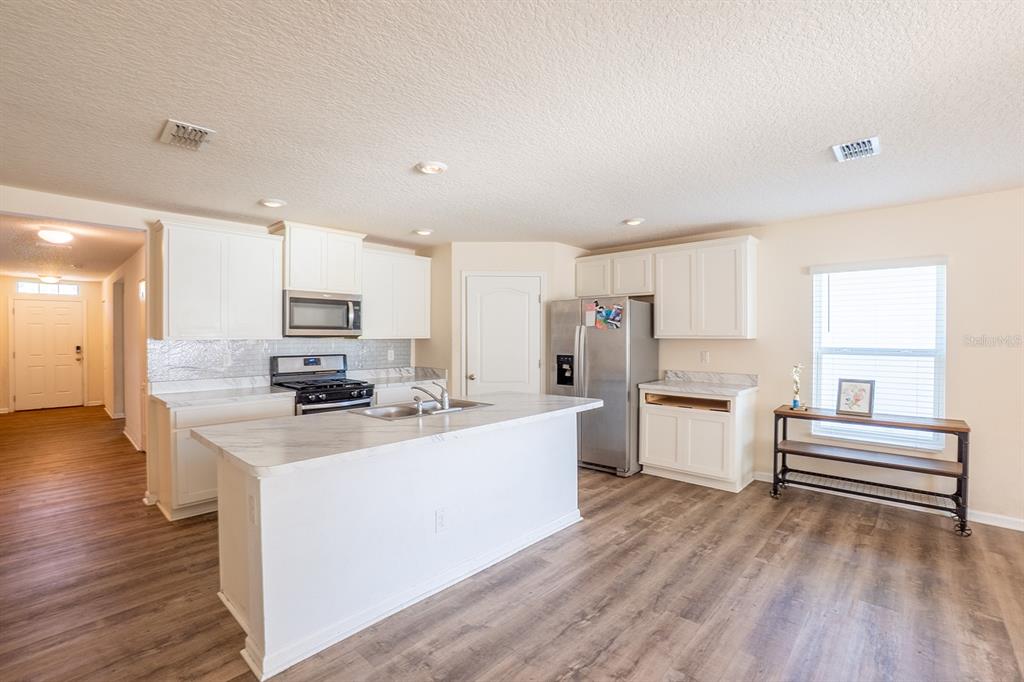 9 Grand Par Court Bunnell, FL 32110 - Photo 15 of 24 a kitchen with stainless steel appliances a stove top oven a sink a refrigerator white cabinets and wooden floor