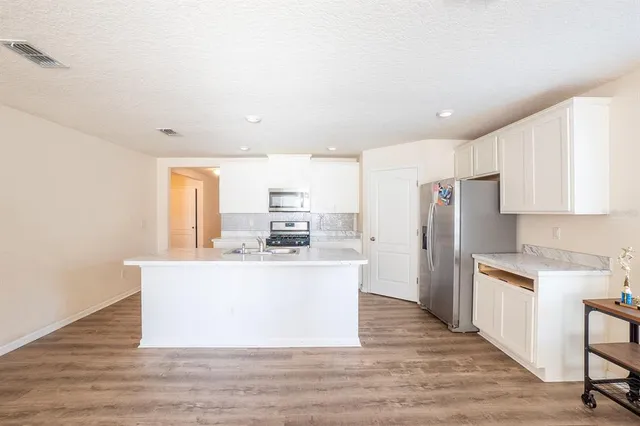 a large white kitchen with wooden floor and a sink