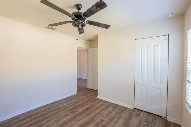 an empty room with wooden floor fan and a ceiling fan