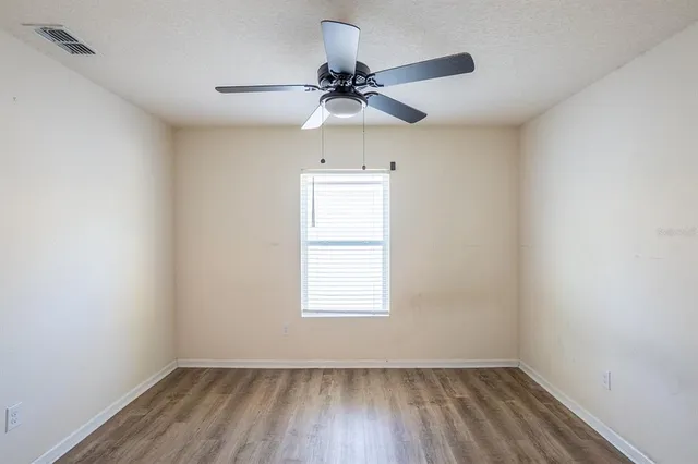 an empty room with a window and a fan