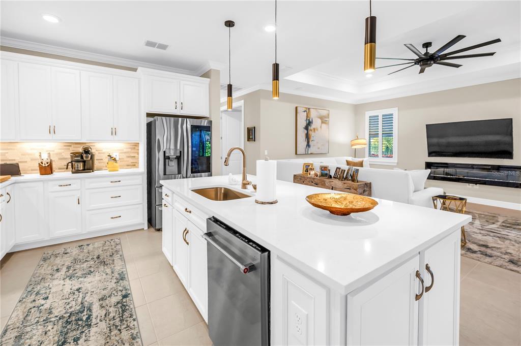 10735 Spring Tide Way Palmetto, FL 34221 - Photo 12 of 41 a kitchen with stainless steel appliances a stove a sink a microwave a refrigerator a stove and white cabinets with wooden floor