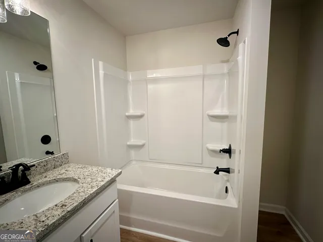 a bathroom with a granite countertop sink mirror toilet and bathtub