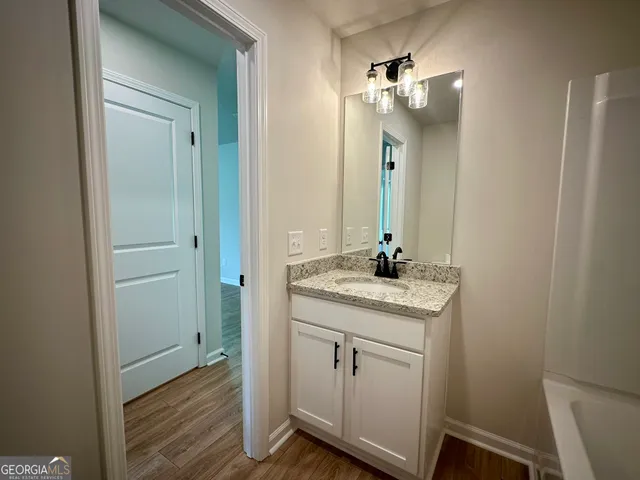 a bathroom with a granite countertop sink a light fixture and a mirror