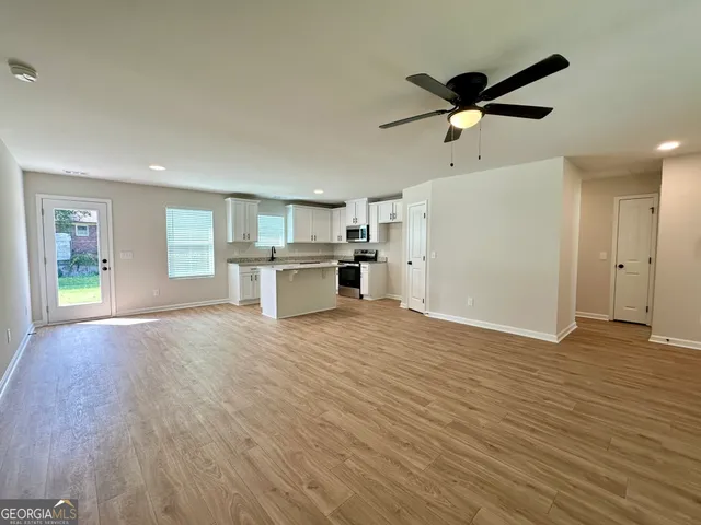 a view of empty room with wooden floor and window