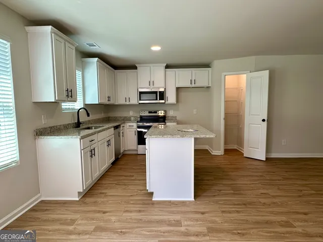 a kitchen with kitchen island granite countertop a sink cabinets and wooden floor