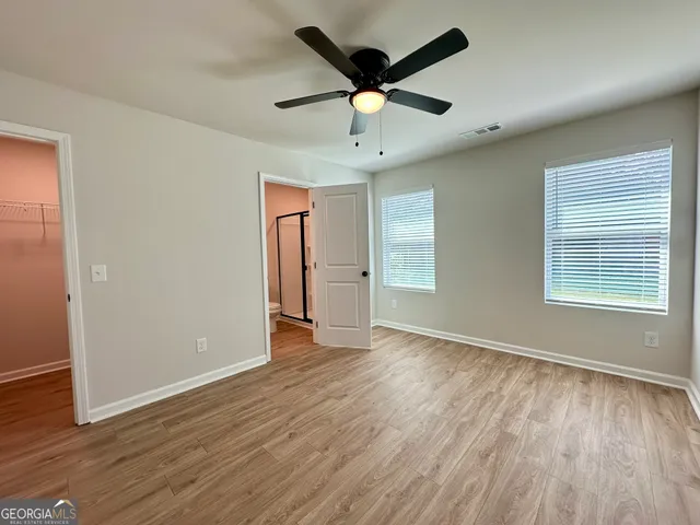 a view of empty room with wooden floor and fan
