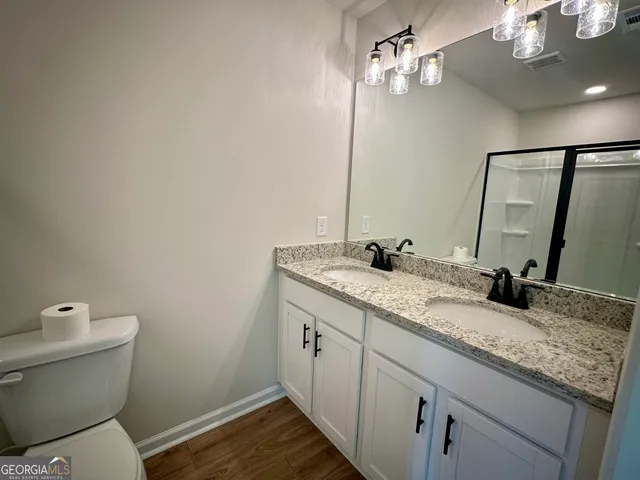 a bathroom with a granite countertop sink a toilet and a mirror