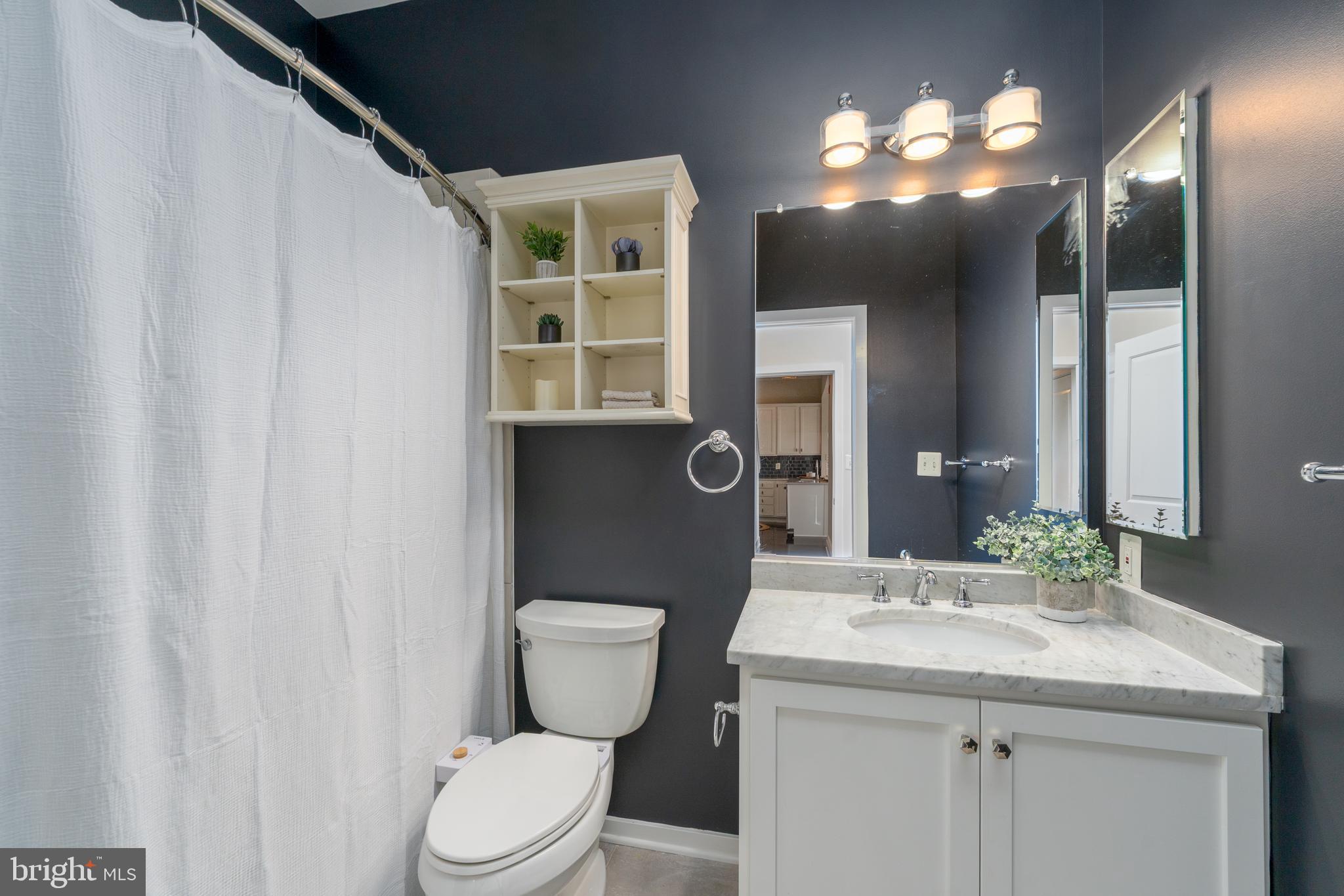 1500 Thames Street, Unit 401 Baltimore, MD 21231 - Photo 19 of 54 a bathroom with a granite countertop sink toilet and a mirror