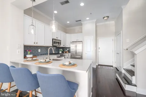 a kitchen with stainless steel appliances granite countertop a refrigerator a stove a sink a dining table and chairs