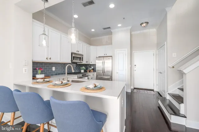 a kitchen with stainless steel appliances granite countertop a refrigerator a stove a sink a dining table and chairs