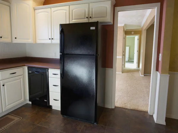 a kitchen with white cabinets and a refrigerator