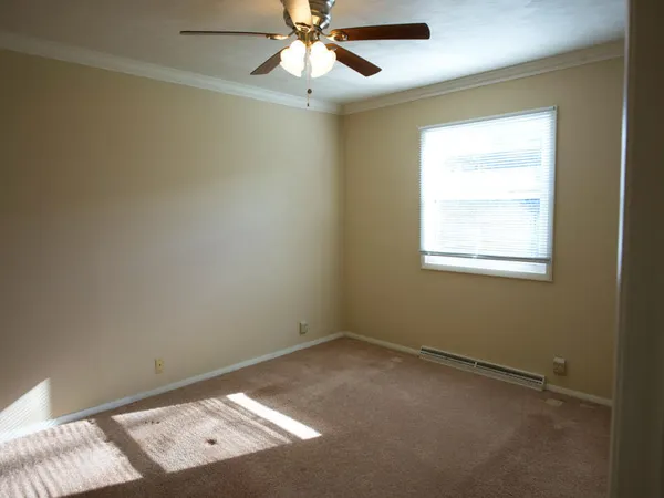 an empty room with a window and a fan
