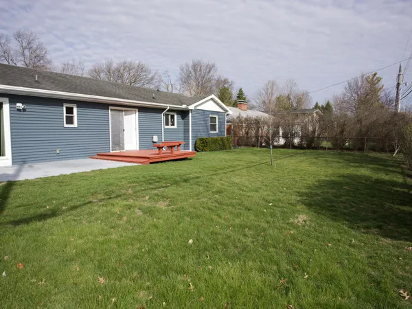 a front view of house with yard and trees in the background