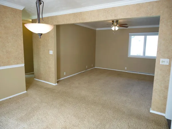 a view of an empty room with a chandelier fan