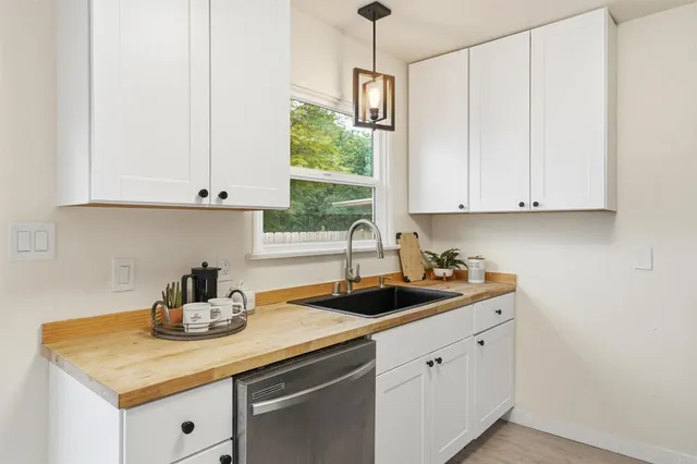 a kitchen with stainless steel appliances granite countertop white cabinets a sink and dishwasher