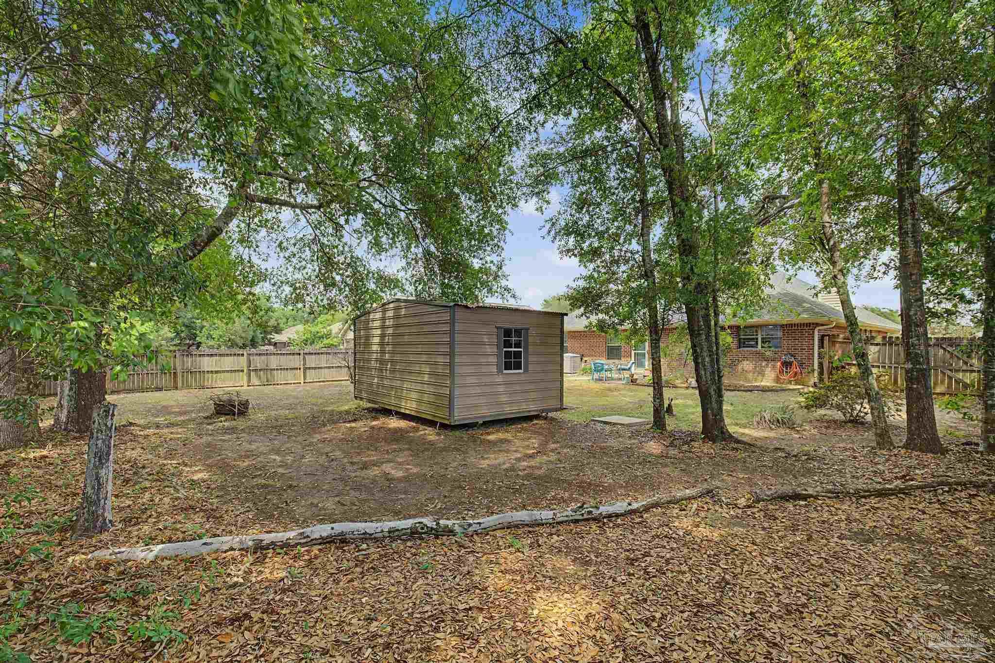 5461 Tucker Circle Pace, FL 32571 - Photo 38 of 52 a view of a backyard with large trees and a barn