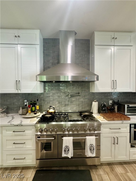 251 Spring Heights Caliente, NV 89008 - Photo 4 of 19 Kitchen with appliances with stainless steel finishes, white cabinets, wall chimney exhaust hood, wood tiled floors, and tasteful backsplash