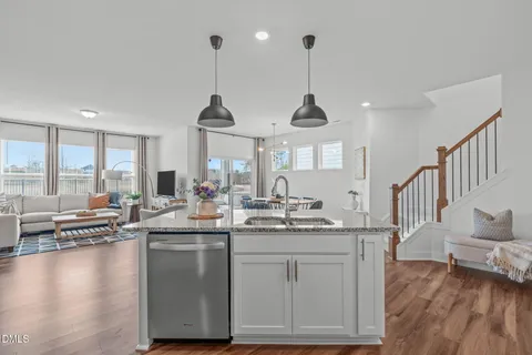 a kitchen with stainless steel appliances granite countertop a refrigerator a sink dishwasher a stove and white cabinets with wooden floor