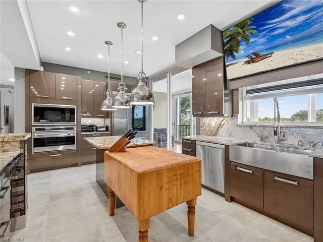 a kitchen with stainless steel appliances kitchen island granite countertop a stove a sink and a refrigerator