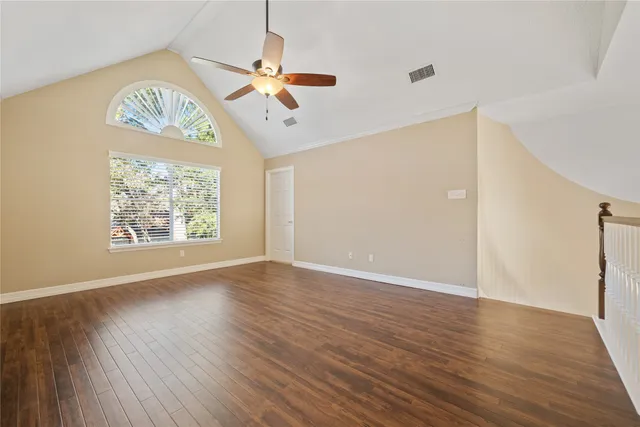 an empty room with wooden floor chandelier and windows