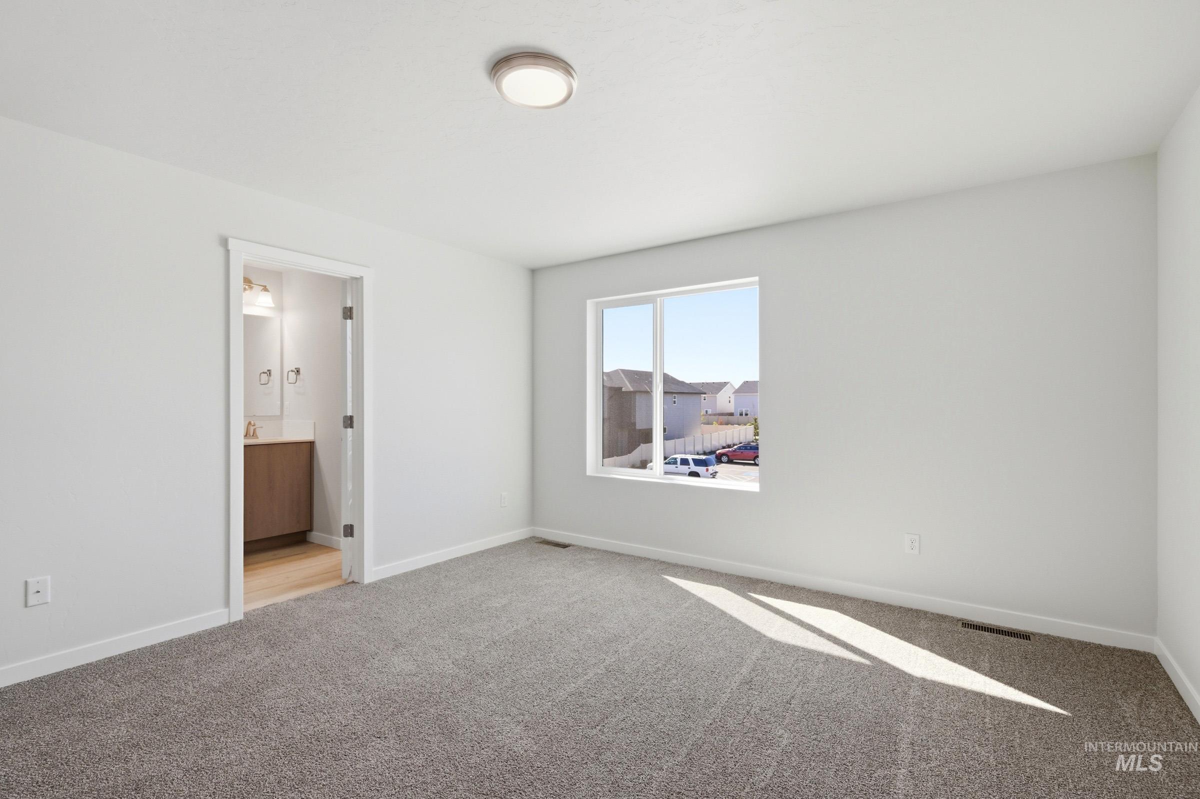 10794 Rutland Street Caldwell, ID 83605 - Photo 21 of 22 Spacious room featuring gray carpeting, a large window, and a contemporary ceiling light fixture